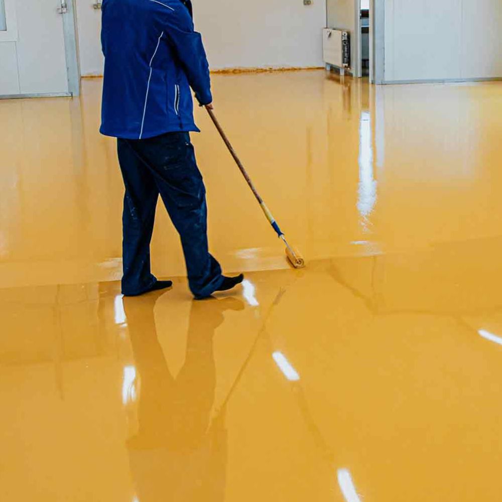 person rolling eposy coating on yellow floor - Innovative Garage Flooring epoxy flooring