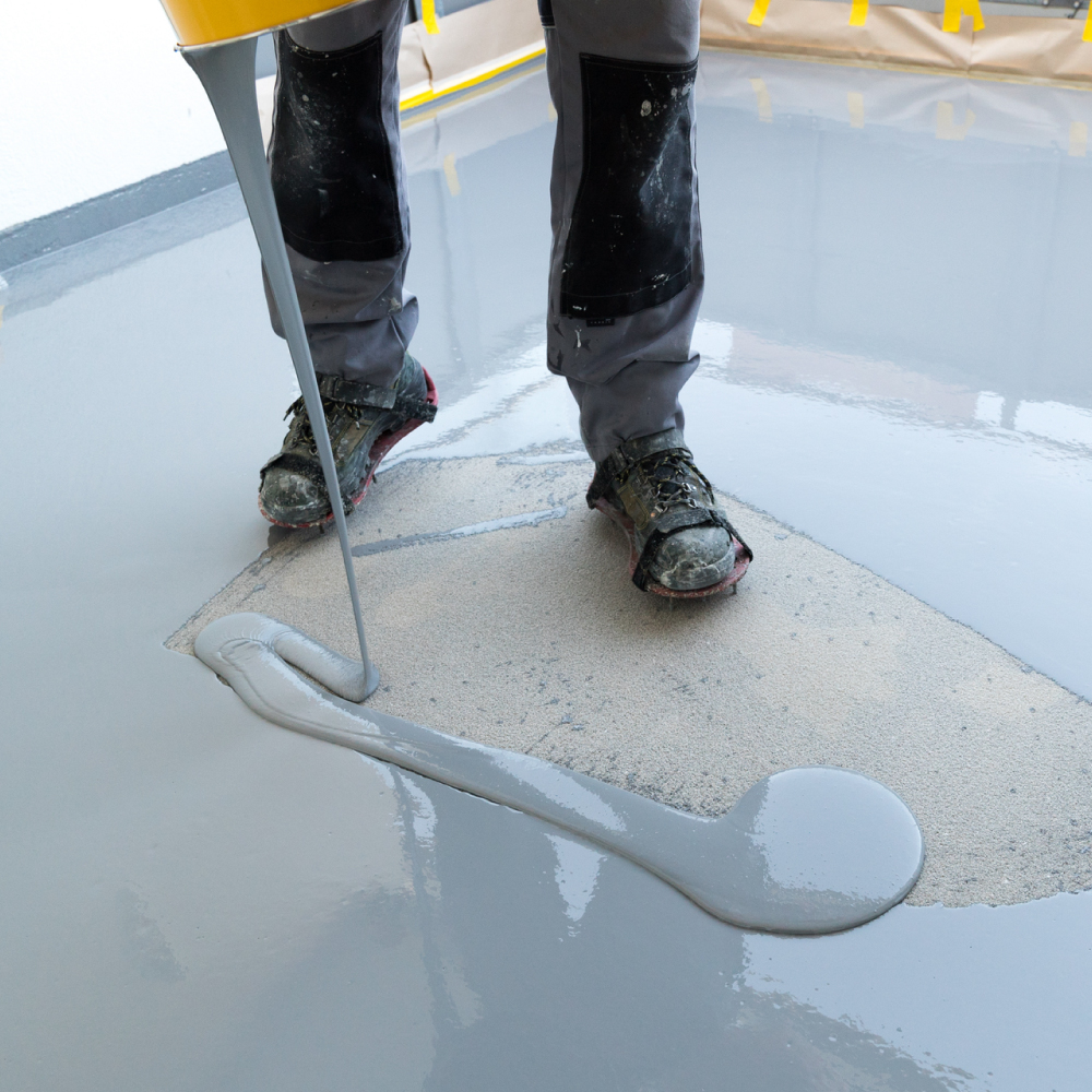 person wearing boots spreading grey epoxy flooring - Innovative Garage Flooring