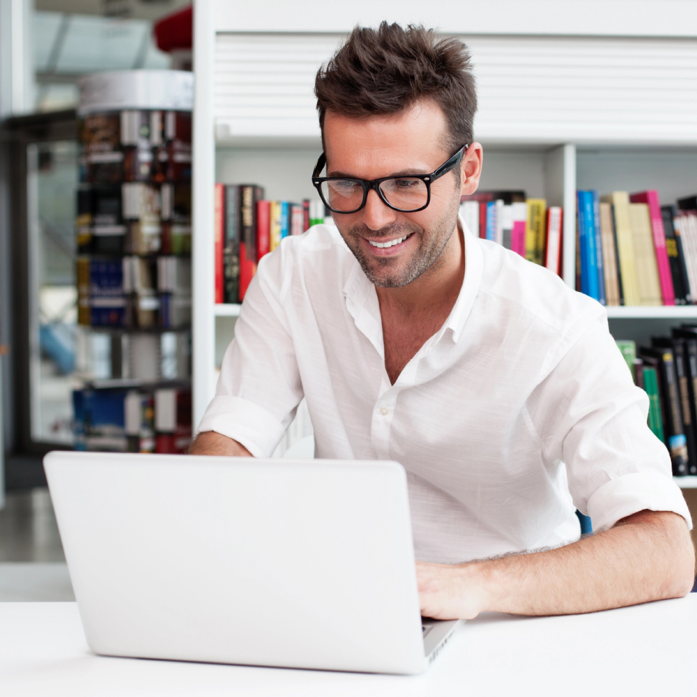 man with black glasses smiling at laptop - Innovative Garage Flooring