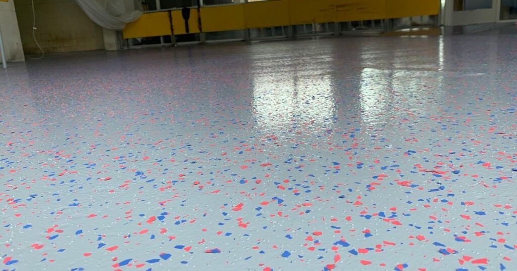 empty building with grey epoxy flooring with orange and blue specs - Innovative Garage Flooring epoxy flooring