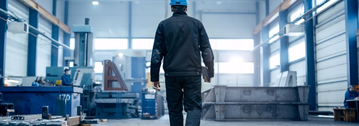 man in a factory wearing a hard hat and holding a clipboard - Innovative Garage Flooring industrial epoxy flooring