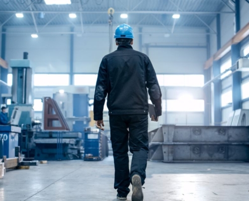 man in a factory wearing a hard hat and holding a clipboard - Innovative Garage Flooring industrial epoxy flooring